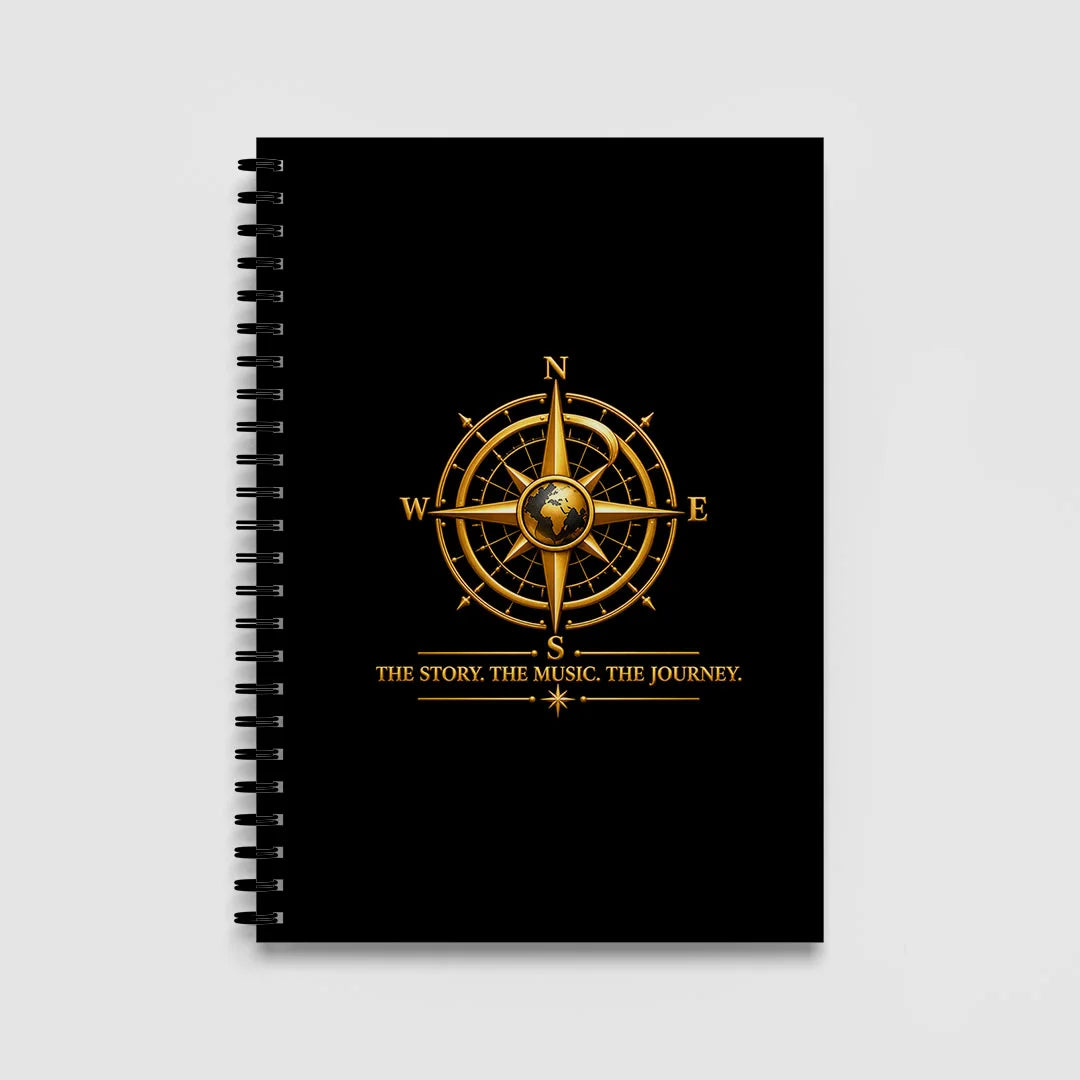 Black A5 spiral notebook with a gold globe compass and THE STORY. THE MUSIC. THE JOURNEY. tagline on the front cover.